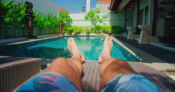 在蓝色游泳池附近度假的时候 人们在休闲地休息 粗壮的男性脚在前景与浓密的深色体毛 娱乐区 日光浴 黄褐色 日光浴 — 图库照片
