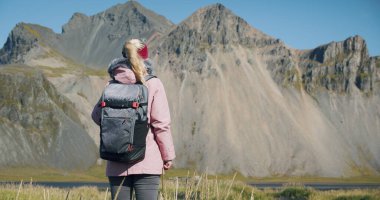 Kadının arka plandaki Vestrahorn dağına bakan Stokksnes 'i keşfetmesi Doğa ve Seyahat Konsepti.