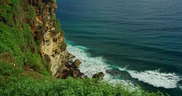 巴厘岛生动的热带海岸 石灰岩陡峭的悬崖和蔚蓝的印度洋波浪 Uluwatu岩石海滩 印度尼西亚 慢镜头 手持录像 — 图库视频影像