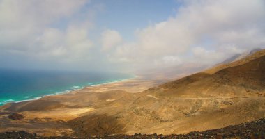 Cofete beach with endless horizon and traces on the sand. Volcanic hills in the background and Atlantic Ocean. Playa de Cofete is longest on Fuerteventura, Canary Islands, Spain. Nobody.