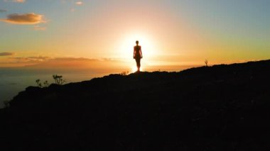 Gün batımında dağın tepesinde bir kadın silueti. Hava aracı. Güneş ışınları insanı benekler. Yürüyüşçü güneşin doğuşunun tadını çıkarıyor. Güneş ışınları okyanustan yükselir. Yalnız kız dikiz aynası.