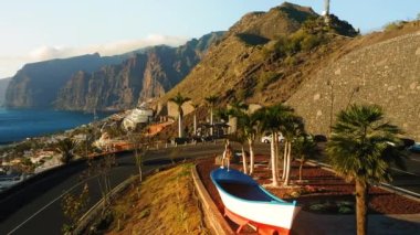 Female tourist by boat observation deck enjoys marine view with Los Gigantes cliffs during summer holiday. Streets of town Puerto de Santiago. Tenerife Canary Islands Spain Europe. Travel concept.