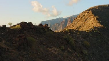 Dik uçurumlar volkanik dağlar İspanya 'nın Tenerife Kanarya Adaları' nın kıyı şeridini oluşturur. Los Gigantes derin mavi okyanus sularıyla sallanıyor. Gün batımında sinematik uçuş. İnanılmaz manzara..