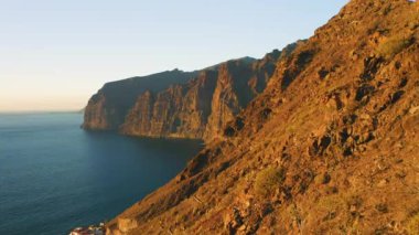 İspanya 'nın Tenerife Canay Adaları' ndaki Guios sahilindeki Los Gigantes uçurumlarının üzerinde günbatımı manzarası. Yüksek volkanik kaya oluşumları. Derin, sakin okyanus suları. Turist eğlencesi.