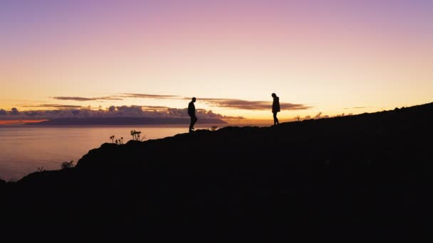 チームワーク2人の観光客の登山者は山の上で会い カラフルな紫色の夕日の間に高い5 薄明夜の自然 曇った空 海を背景に テネリフェ島カナリア諸島スペインヨーロッパ — ストック動画