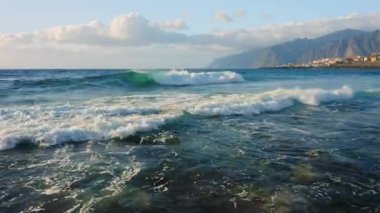 Ocean landscape with rocky coastline volcanic seaside of Punta Juanita Beach on Tenerife Canary Islands. Clouds on sky. Aerial flight over sea foamy waves crash on wild shore. Scenery. Amazing nature