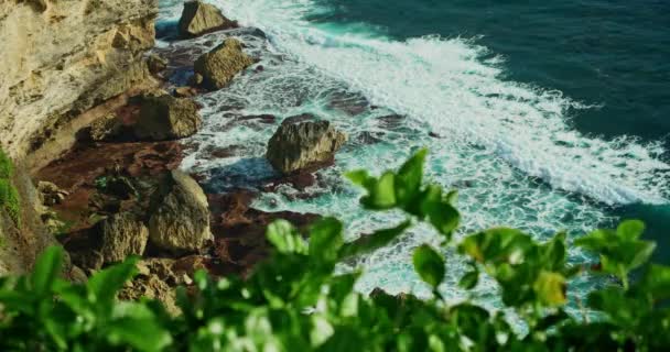 石灰岩の切り立った崖と紺碧のインド洋の波とバリ島の活気に満ちた熱帯海岸 ウルワツ岩礁のビーチ インドネシア スローモーション静止画 — ストック動画