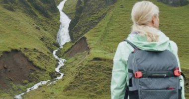 İzlanda 'nın güney kıyısında Fjadrargljufur yakınlarında izlanda şelalesinin keyfini çıkaran sırt çantalı bir kadın turist.