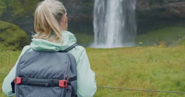Güzel Seljalandfoss Şelalesi İzlanda 'ya giden sırt çantalı kadın gezginin yakın çekimi.