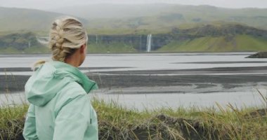 Güzel İzlanda şelalesinin keyfini çıkaran kadın Seljalandsfoss