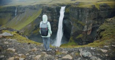 Sırt çantalı kadın İzlanda 'da Haifoss şelalesinin keyfini çıkarıyor.