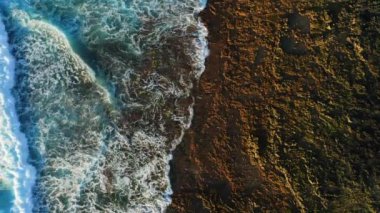 El değmemiş kayalık volkanik kıyı şeridi ve beyaz köpüklü dalgalı turkuaz okyanus suyu. Havadan aşağıya statik dron görüntüsü. Tenerife Kanarya Adaları.