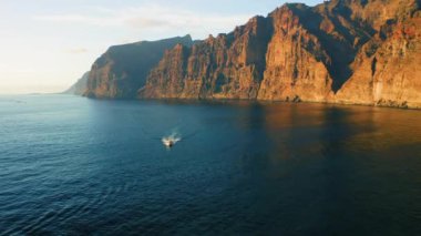 Los Gigantes uçurumlarındaki devasa kayalık dağlar Tenerife 'de. Açık denizde beyaz tekne. Tatil seyahati konsepti. Her yere git.