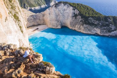 Yunanistan 'ın Zakynthos Adası' ndaki gemi enkazı plajından keyif alan kadın turistin hava manzarası. Yaz yolculuğu konsepti.