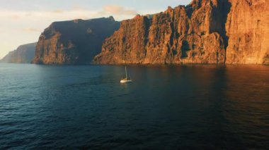 Los Gigantes kayalıklarında okyanusta yüzen yalnız bir yat Tenerife 'de. Tatil ve seyahat kavramı.