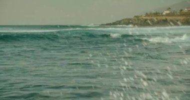 Yakın çekim okyanus dalgaları kayalık sahilde mavi gökyüzüne çarpıyor. Tenerife Kanarya Adalarının Doğa ve Manzarası.