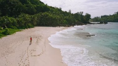 Cennetteki genç kadın Anse Bazarca plajı ışıklandırması. Güzel Mahe Adası 'ndaki bronzlaşmış kızın hava görüntüleri. Seyahat kavramı