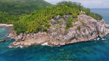 Seyşeller 'deki Mahe Adası' nda mercan resifi ve mavi okyanus suyuyla 4K hava sahasında egzotik tropikal orman adasında uçar.
