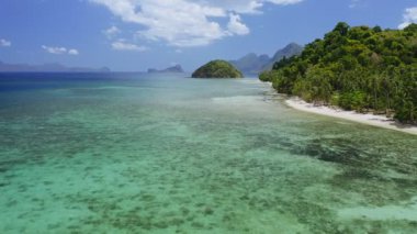 El Nido tropikal sahil kıyı şeridinin 4k Aerial manzarası. Birçok palmiye ağacı ve sığ sularda eski mercanlar var. Palawan, Filipinler. Yaz ve seyahat tatil konsepti