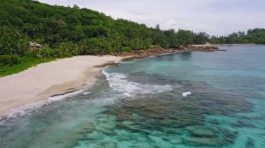 Okyanus dalgalarının beyaz kum cennetindeki havadan görünüşü tıpkı Mahe Adası, Seyşeller 'deki tropikal plaj Anse Bazarca' sı gibi. Yaz tatili, seyahat ve yaşam tarzı konsepti