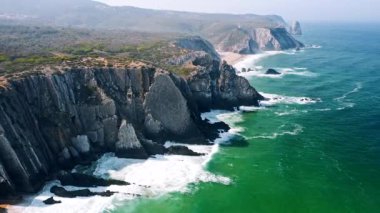 4K Atlantik okyanus dalgaları ve kayalık uçurumların manzarası Praia Grande plajı, Portekiz