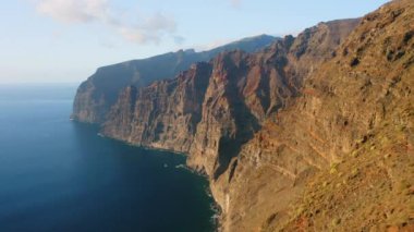 Güzel dağ günbatımı uçurumları. Derin okyanus üzerinde inanılmaz bir uçuş mavi su, kahverengi ve kırmızı renkli büyük kayalar. Giants Tenerife Adası. Dünyayı dolaş. Canlı renkler.