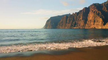 Gözlerden uzak siyah kumsal Playa de los Guios köpüklü dalgalarla. Okyanustaki Los Gigantes uçurumları. Tenerife Kanarya Adaları İspanya.