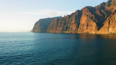 Tenerife 'deki Los Gigantes kayalıkları ile okyanus manzarası. Açık denizde yelken açan tekneler. Tatil seyahati konsepti. Her yere git.