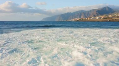 Tenerife Kanarya Adaları 'ndaki Punta Juanita Sahili' nin kayalık kıyı şeridi ile okyanus manzarası. Gökyüzündeki bulutlar. Deniz köpüğü vahşi kıyıya çarpar. Manzara.