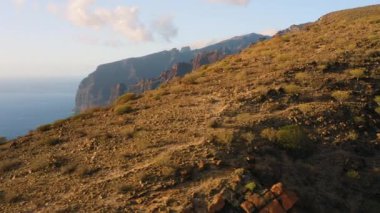Los Gigantes 'in dramatik deniz manzarası. Tenerife Kanarya Adası' ndaki büyük, çorak uçurumlar. Sakin, temiz, derin okyanus denizi. Volkanik kayalık plaj hava sineması uçuşu.