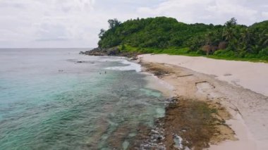 Mahe Adası, Seyşeller. Havadan alçak irtifa, egzotik kumlu sahilde dalgalarla oynayan turistlerle uçuyor. Yaşam tarzı. seyahat ve dinlenme kavramı