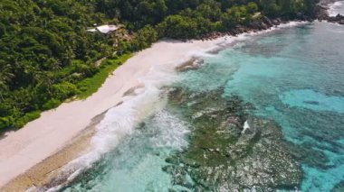 Seyşeller. Gözlerden uzak tropikal kumsalın havadan görünüşü mavi göldeki okyanus dalgaları ve eski mercanlar. Yaz tatili, seyahat ve yaşam tarzı konsepti