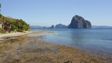 Filipinler, Palawan 'daki El Nido köyünün tropikal plajı boyunca 4k Aerial uçuşu. Turistler akşam vakti dalgalar alçaldığında rahatlar ve kıyıları keşfederler