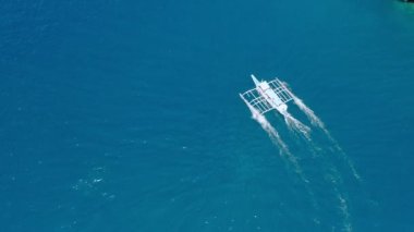 Güneşli bir günde açık denizde turkuaz ve berrak suyla hareket eden teknenin hava aracı görüntüsü. Tekne tropikal gölden ayrıldı. El Nido, Palawan Adası, Filipinler