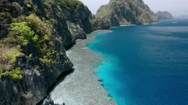 Matinloc tapınağı yakınlarındaki kayalık dağların ve mercan resiflerinin üzerinden uçan hava görüntüleri. El Nido, Palawan Filipinleri
