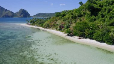 4k hava aracı, sığ sularda ve hindistan cevizi palmiyelerinde yerel teknelerle tropikal kumlu sahilde uçuyor. El Nido. Palawan, Filipinler