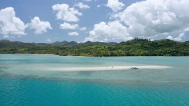 Kum yığınının etrafında dönen hava aracı görüntüleri. Beyaz bulutlar ve arka planda ana kara. El Nido, Palawan, Filipinler