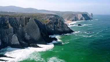 4K Aerial still view of Praia Grande beach, Portugal. Atlantic ocean waves and rocky cost cliffs in front.