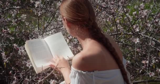 Femeie Citind Carte Hârtie Grădina Primăvară Doamnă Carte Relaxantă Natură — Videoclip de stoc