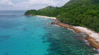 Seyşeller 'deki Mahe Adası' ndaki tropikal ada kıyı şeridi, mercan resifi ve mavi lagünün havadan 4K görüntüsü.