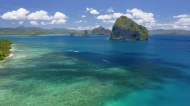 Okyanus yüzeyinde hareket eden bulut gölgeli Pinagbuyutan adasının insansız hava aracı görüntüsü. Denizdeki banka tekneleri. El Nido, Palawan, Filipinler.