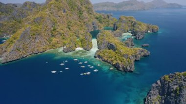 Engebeli Miniloc Adası 'nın 4k hava manzarası. El-Nido, Palawan. Filipinler. Büyük Göl 'ün önüne demirlemiş turist tekneleri. A Tur.