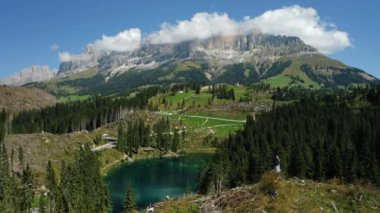 Carezza Gölü 'ndeki güçlü rüzgârdan sonra köklerinden sökülmüş çam ağaçlarıyla tepedeki kadınlar. Güney Tyrol' daki en güzel göller, Dolomitler. İnsansız hava aracı hareketini çember.