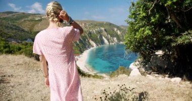 Dağın tepesinde gezgin bir kadın güzel deniz koyuna bakıyor manzaralı manzarayı kutluyor tatil macerasının tadını çıkarıyor doğa.