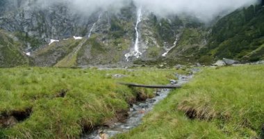 Stubai vadisi, Avusturya. Arka planda güzel bir şelaleyle dağ nehrinin üzerinde yürüyüş yapmak. Açık hava turizmi kavramı.