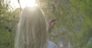 Kahverengi kadın saçının yumuşak hareketini yaz günbatımında yavaş çekimde yakından izleyin. Esmer ya da kızıl saçlı kadın alacakaranlıkta beachi 'nin üzerinde duruyor. Rüzgar, güneşin doğuşunda parlayan havadar saçlarını savurur.