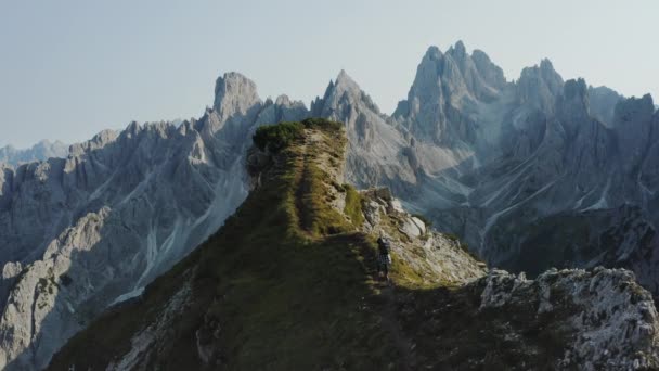女性は崖の端に沿って歩く 背景にイタリア ドロミテ州のカディーニ ミスリナ山脈群 Cime Levaredo国立公園とユネスコの世界遺産があります 空中ドローン映像 — ストック動画