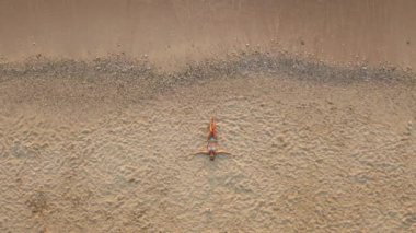 Kumsaldaki kadın turistin ve sahil kenarındaki turkuaz deniz dalgalarının aşağı manzarası. Yaz sahnesi turizmi konsepti