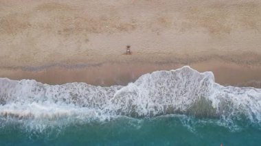 Kumsaldaki erkek turistin ve sahil kenarındaki turkuaz deniz dalgalarının en alt görüntüsü. Yaz sahnesi turizmi konsepti