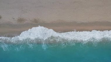 Kumlu sahil manzarası ve kıyı kenarındaki turkuaz deniz dalgaları. Yaz sahne kenarı hareketi